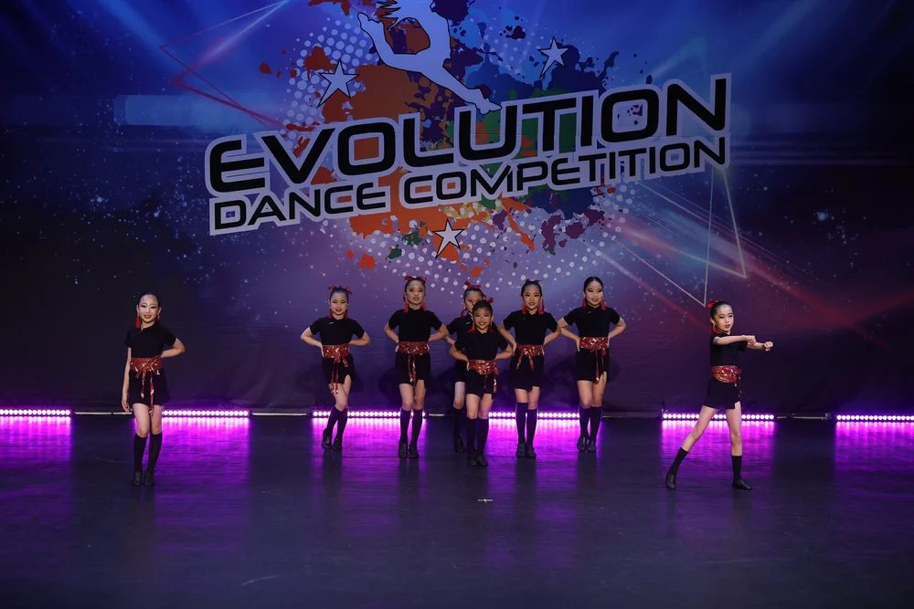 Dancers in a line under purple stage light