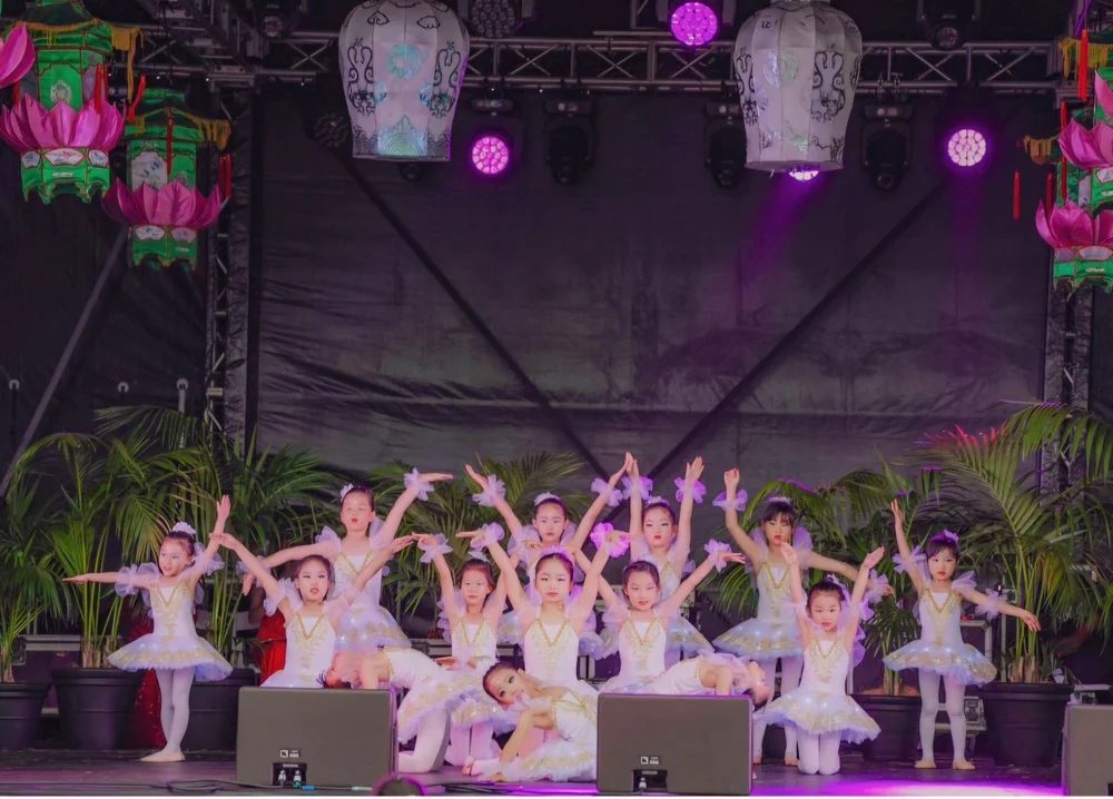 Young dancers in white on a lantern-lit stage